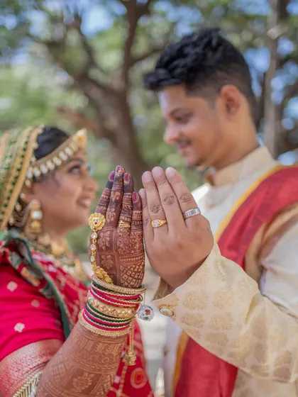 A symbolic photo of the bride and groom showing their wedding rings and mehndi-covered hands.