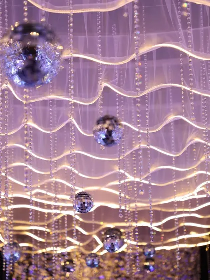 A close-up of the sangeet pathway ceiling, showing the delicate crystal strings and mini disco balls that create a starry night effect.