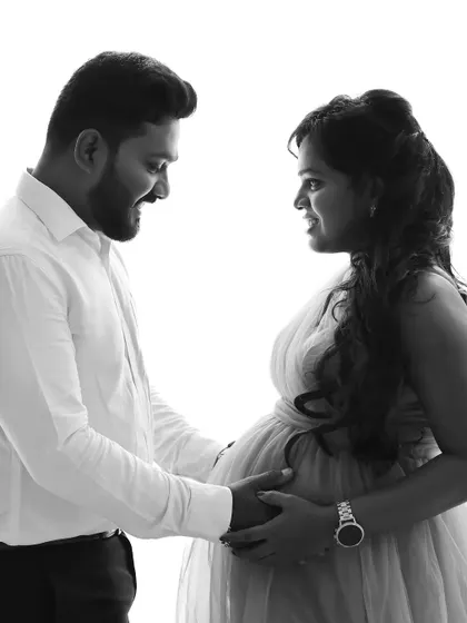 A close-up black and white shot capturing the joyful interaction between a couple during their maternity photoshoot.
