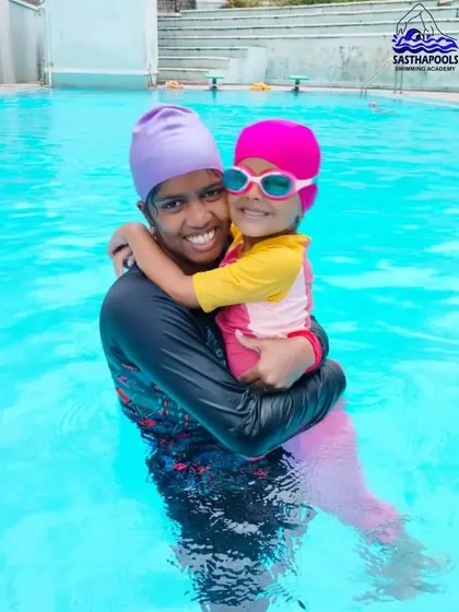 A joyful moment between an older and younger swimmer during our summer camp. We foster a supportive community where swimmers of all ages can learn from and encourage one another.