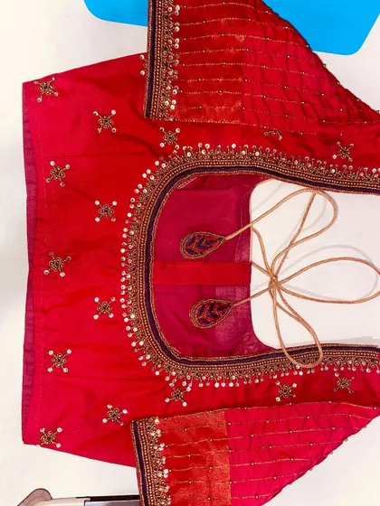 This red blouse is decorated with small sequin and bead motifs all over. The neckline and sleeves have a simple, elegant border.