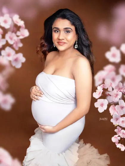 A gorgeous close-up portrait. The soft floral framing and the elegant white gown create a truly romantic and beautiful image of this glowing mom-to-be.