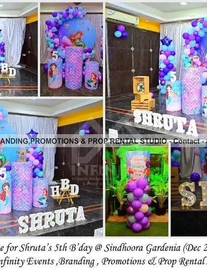 An underwater adventure awaits with this Mermaid theme for a 5th birthday. The decor features a circular backdrop, a purple and blue balloon garland, and themed cylinder props, creating a magical seascape for the celebration.