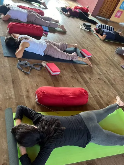Students in a Yin class hold a gentle, restorative pose, using props to find comfort and release.
