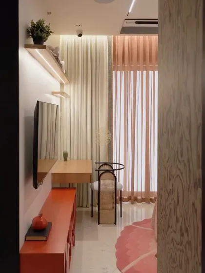 A glimpse into the kids' room, showing the study nook and the bright orange media unit. The sheer curtains allow for plenty of natural light while adding a soft touch to the space.