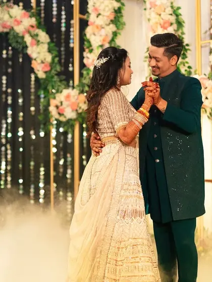 The couple's romantic dance at their Sangeet. Framed by a beautiful floral arch and sparkling lights, they are lost in their own world, creating a picture-perfect memory.