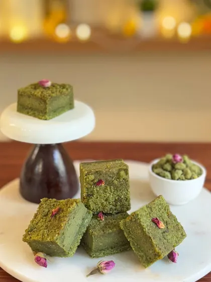 The Pistachio Crumble Cheesecake squares, garnished with delicate rosebuds. The vibrant green from real pistachios makes this dessert a visual and flavorful celebration of gratitude.