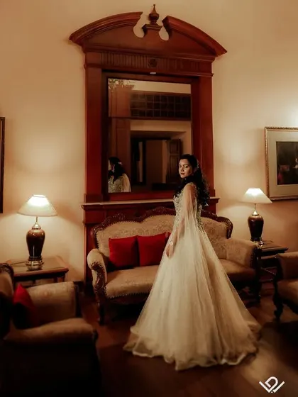 An elegant, full-length portrait of a bride-to-be in a beautiful gown, set in a classic, vintage-style room.