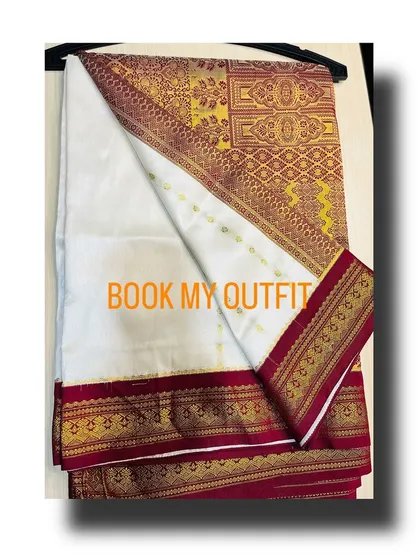 The off-white silk saree features a rich woven gold and maroon border, offering a timeless and sophisticated look.