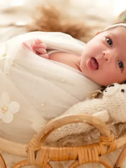 This little one is awake and playful, sticking her tongue out for the camera from her cozy basket.