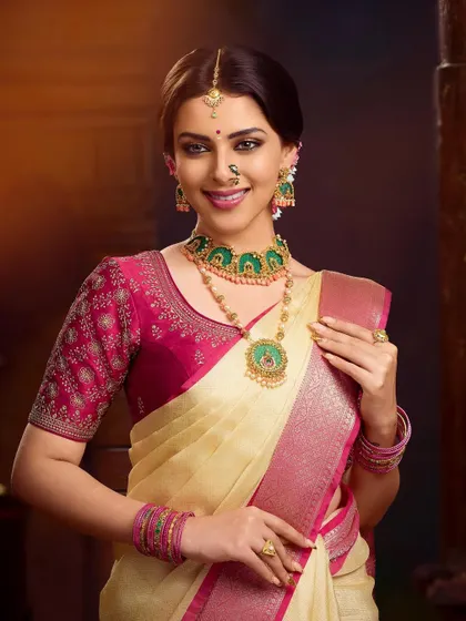 This portrait showcases a different jewelry set against the same beautiful saree. The green enamel work in the necklace and earrings offers a striking contrast to the pink blouse.