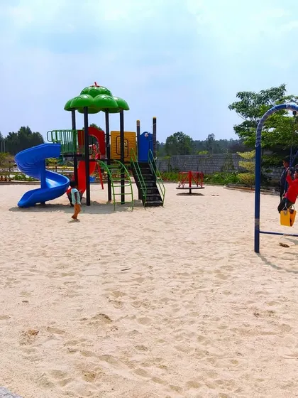 A completed sand-based playground at 'The Sanctuary', featuring a slide, swings, and a see-saw, providing a classic and safe environment for children to play.
