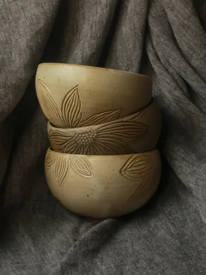 A stack of bowls from the 'Gulbaan' Collection, showcasing the delicate hand-carved floral details. Each piece is a celebration of earth and bloom.