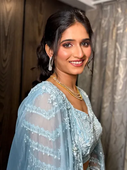 A happy, smiling portrait of the client in her beautiful blue sangeet outfit.