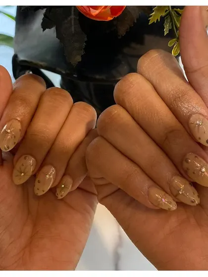 A subtle and classy design. These almond-shaped nails have a neutral beige base with delicate, scattered gold dot patterns, creating a sophisticated and understated look.