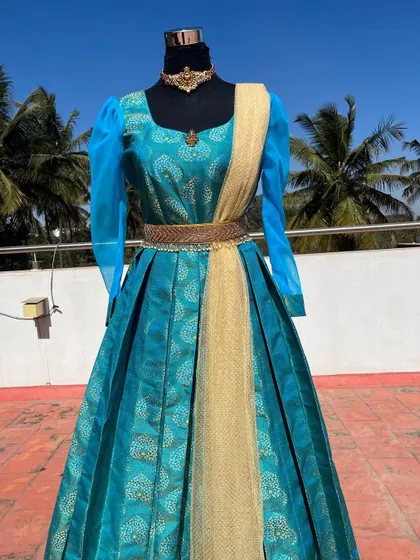 A traditional long gown in teal blue with sheer puff sleeves.
