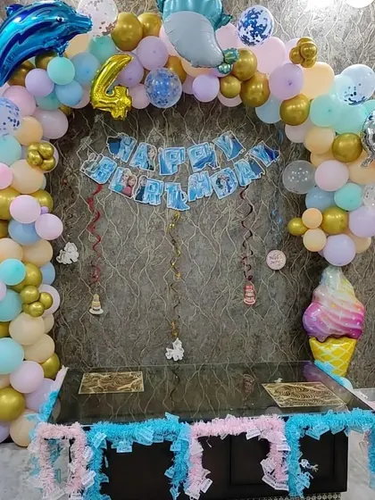 An under-the-sea themed birthday decoration for a 4th birthday. I created a balloon arch with pastel and gold balloons, adding dolphin and ice cream foil balloons for a fun touch over the cake table.