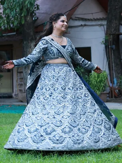 Create a striking reception or sangeet look with this heavily embroidered navy blue lehenga. The intricate silver work photographs beautifully and adds a touch of glamour to any makeup artist's portfolio.