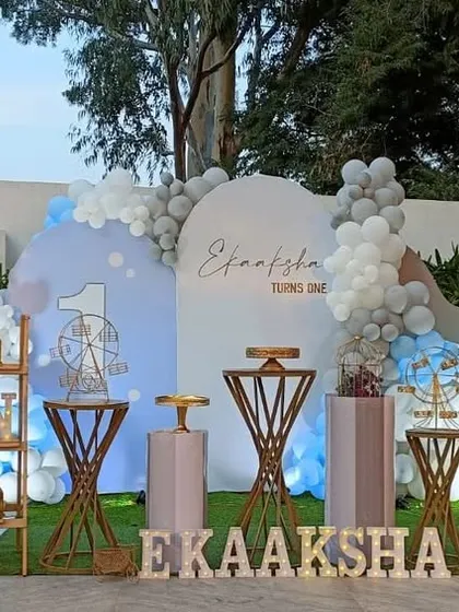 A full view of the winter-themed birthday party. The stage is set with multiple backdrops, themed props like a penguin and polar bear, and a photo collage of the baby's first year.