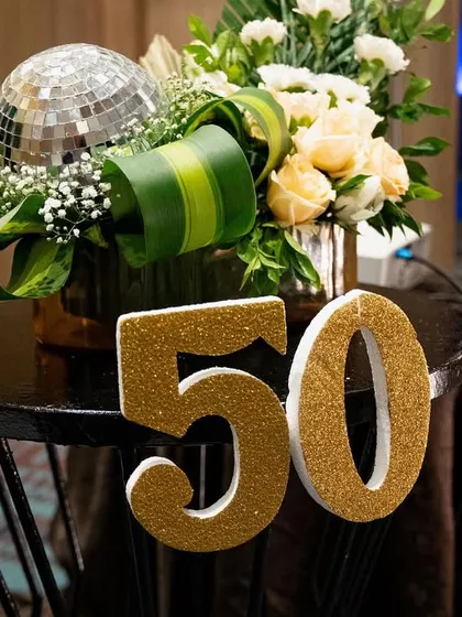 Details from the 50th birthday party. A glittery "50" sign, a mini disco ball, and a beautiful floral arrangement on the side table helped carry the festive and glamorous theme throughout the entire venue.