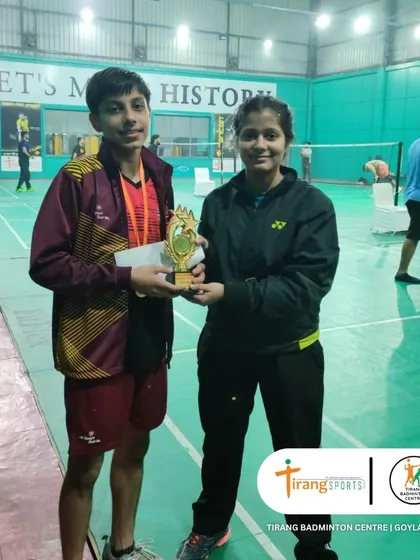 A coach presents a trophy to a deserving winner at the Shuttle Shufflers tournament. The guidance of our coaches is instrumental in our players' success.
