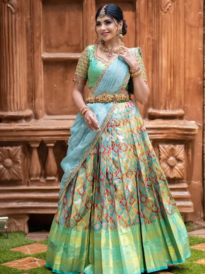 A stunning half saree with a multi-colored ikkat-style Kanchipuram lehenga, paired with a sea-green hand-embroidered blouse.