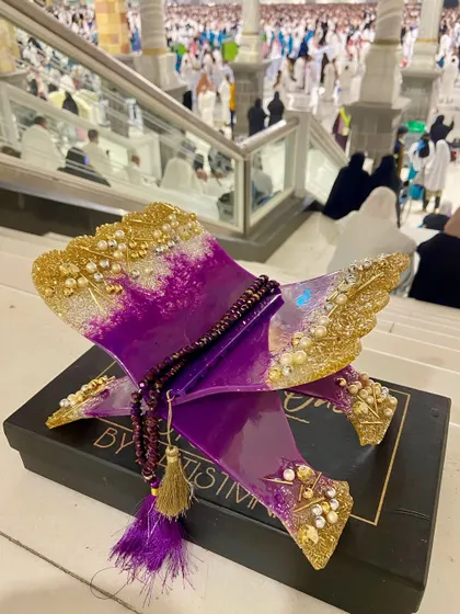 Another shot of the purple and gold Quran holder in Makkah, this time with a crystal tasbih draped over it.
