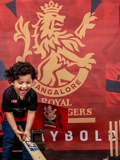 A great action shot from the RCB cricket theme, capturing the little fan's excitement as he swings the bat.
