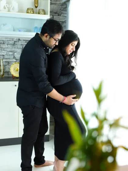 A beautifully lit, intimate portrait of a couple at home, focused on their connection and the baby bump.
