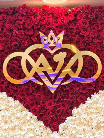 A close-up of a custom gold acrylic monogram, designed with the couple's initials. This personalized element was placed atop a floral heart wall, adding a layer of bespoke luxury to the decor.