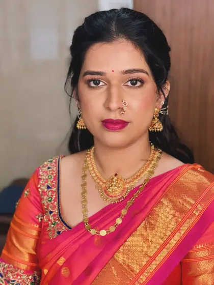 The makeup is clean and defined, perfectly complementing her traditional pink and orange silk saree.