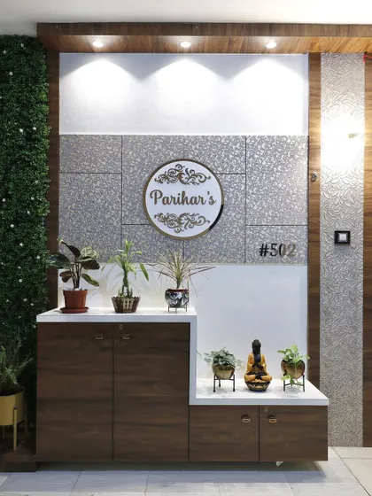An entrance foyer designed with a mix of textures, including a green wall, wood paneling, and silver textured panels. A custom nameplate and a multi-level shoe cabinet with display niches create a functional and stylish entry.