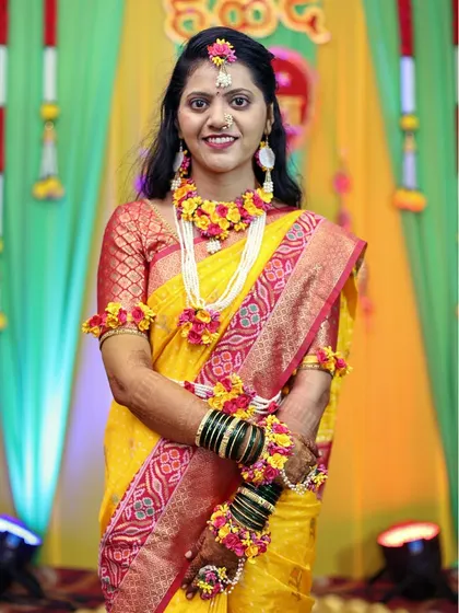 The bride smiling during her Haldi ceremony, adorned with floral accessories.