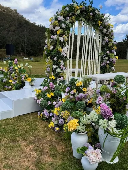 A lush and colorful floral arch in an open field, showing our ability to create beautiful decor in any location.