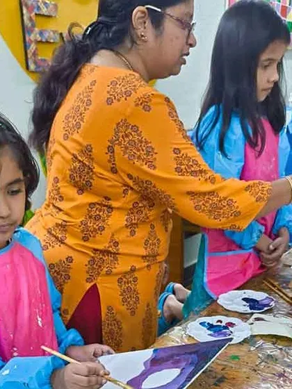 I love guiding my students as they learn new techniques. Here, I'm helping a young artist with color blending on her canvas, ensuring she feels confident and supported.