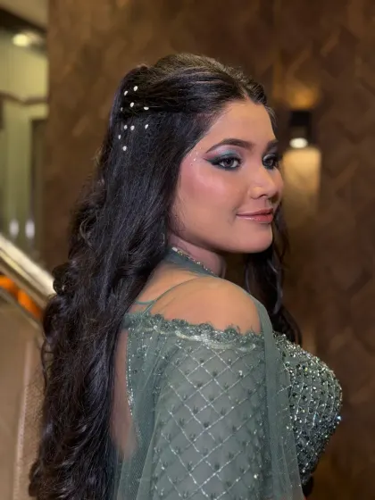 A glamorous look for a sangeet or cocktail party, featuring a dramatic blue-green smokey eye and hair adorned with delicate pearls.