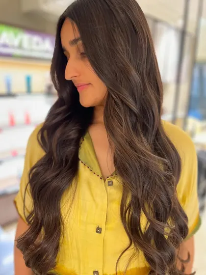 The client looking radiant with her new peek-a-boo highlights. The subtle color and soft waves create a beautiful, natural-looking style.