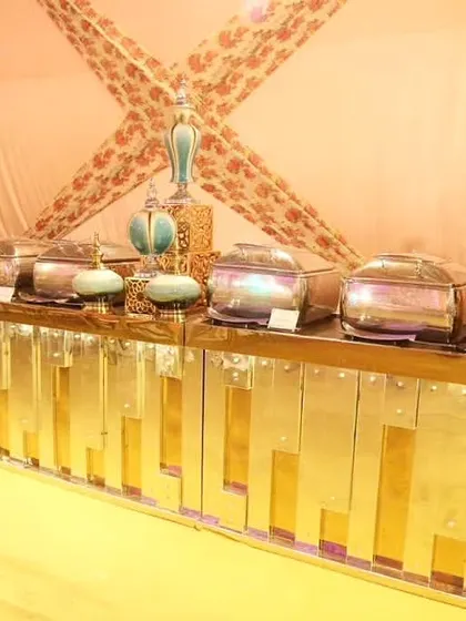 An opulent buffet setup with a gleaming gold-paneled counter. The display is accented with turquoise vases and intricate gold candelabras, creating a luxurious look for a grand wedding.