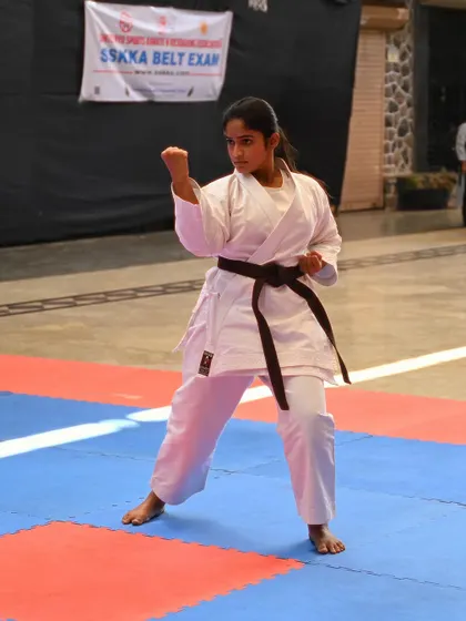 A student demonstrates a powerful stance during her brown belt examination. Her focus and form show she is ready for the next level.
