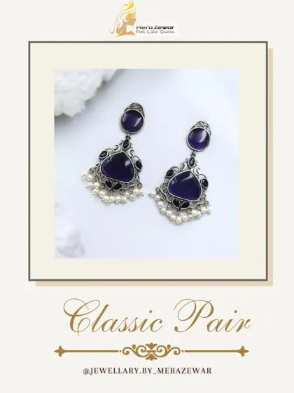 This classic pair of dangle earrings features a deep purple stone with a silver oxidized setting and delicate pearl accents. It's an elegant choice for any occasion.