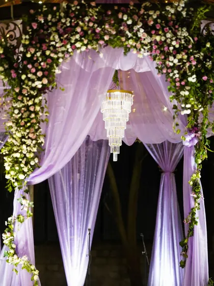 A dreamy combination of lavender drapes and a sparkling crystal chandelier. This decor element creates a soft, romantic, and utterly magical ambiance for an evening celebration.