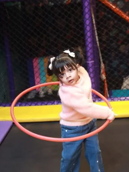 This little girl is mastering the hula hoop on our trampoline, combining two fun activities into one. It's a great way to practice balance and have a laugh.