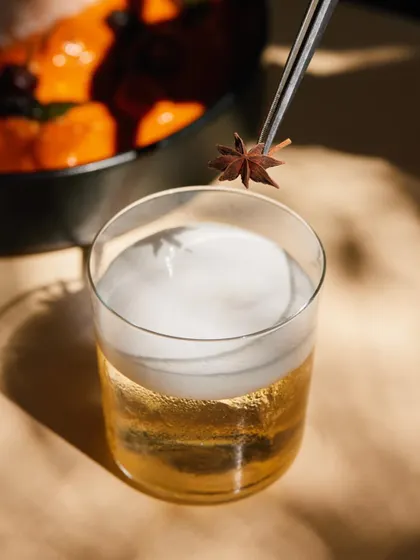 The Cuban Sour, garnished with star anise, sitting next to a bowl of our flavourful curry. A perfect food and drink pairing.