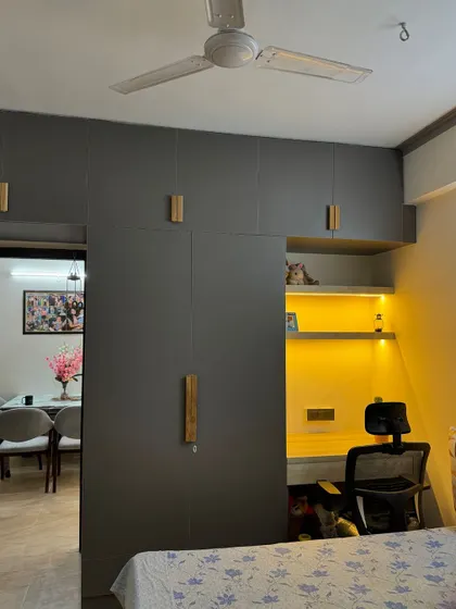 This bedroom features a floor-to-ceiling grey wardrobe with a built-in, backlit study nook. It's a perfect solution for a compact room or for a work-from-home setup.
