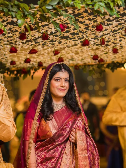 A close-up of the bride under the 'phoolon ki chadar', her happy and confident smile shining through.