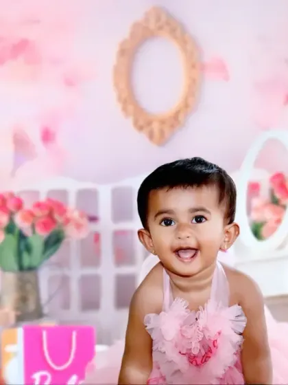 A happy baby girl in a pink tutu dress, smiling with pure joy in a dreamy, all-pink room setup.
