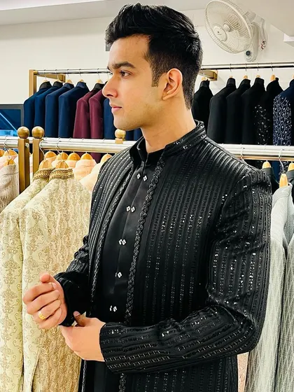 A client trying on a black sequined Indo-western jacket, perfect for a cocktail party or sangeet night.
