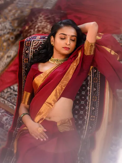 A serene, artistic pose capturing the model in a moment of quiet elegance. The use of traditional carpets and soft lighting creates a warm and inviting atmosphere.