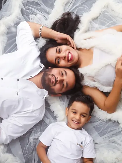 A creative and fun family portrait taken from above. The parents and their son lie together, looking up at the camera with big smiles, creating a unique and memorable shot.