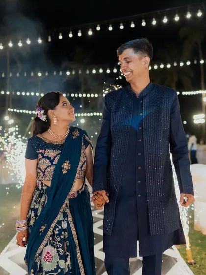 A close-up of the happy couple during their Sangeet entrance, with the warm glow of the string lights and the excitement of the sparklers creating a perfect photo opportunity.